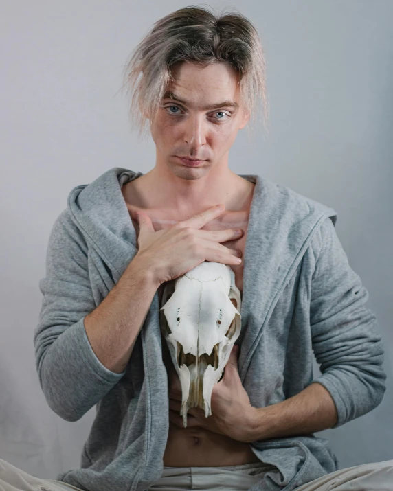 a male is posing with a animal skull