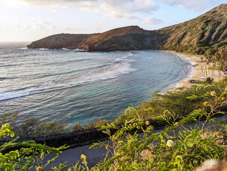 a beach with waves breaking in and a mountain to the left