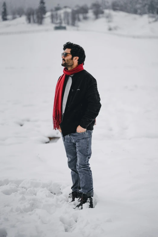 a man standing in the snow with a red scarf on