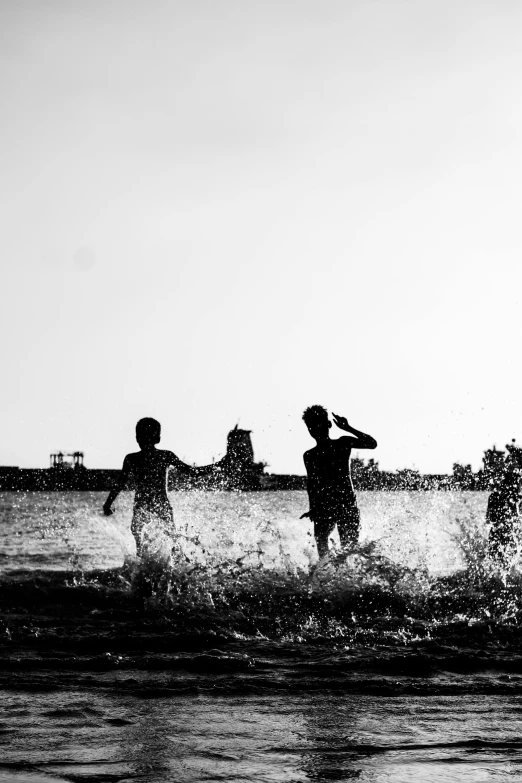 two s playing in the water in front of a clock tower