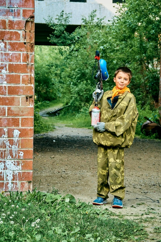 a small boy in camouflage holds a ski pole