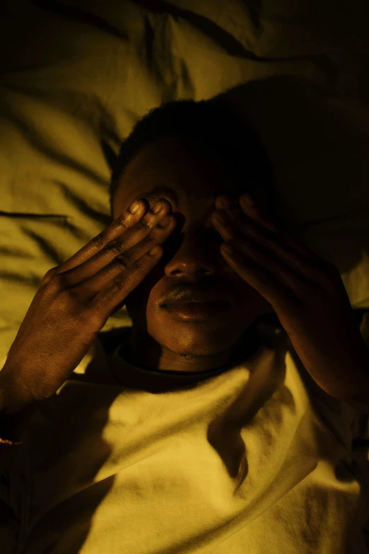 a woman laying on top of a bed with her hands over the eyes