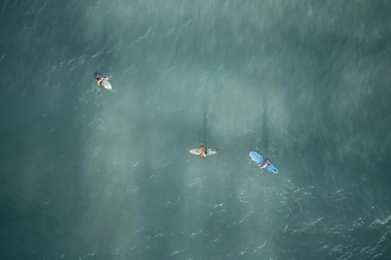 three people are on their surf boards paddling in the ocean