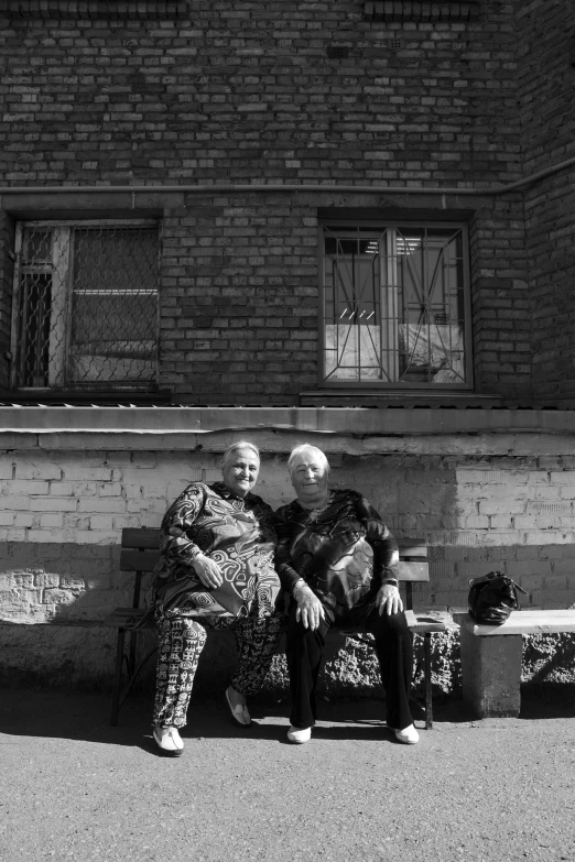 two elderly people sitting on a bench outside