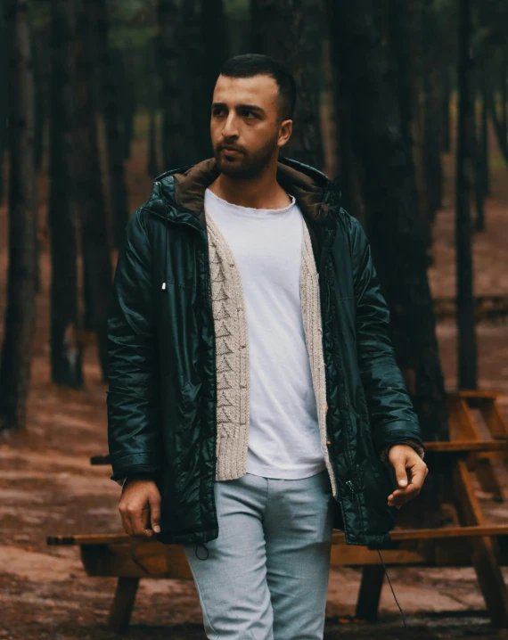 a man wearing white shirt and jeans standing by a bench