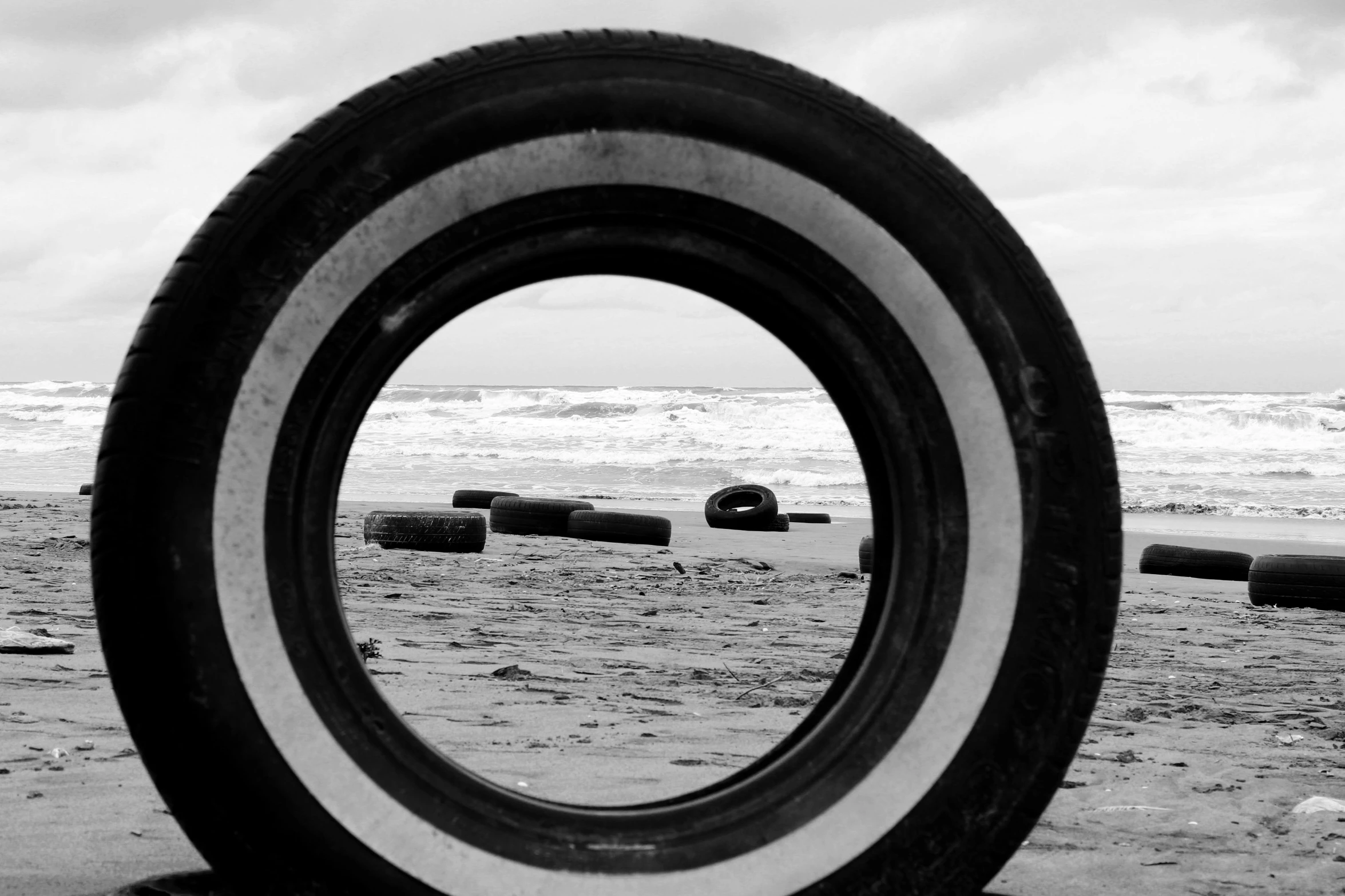 tire sitting on the beach next to the ocean