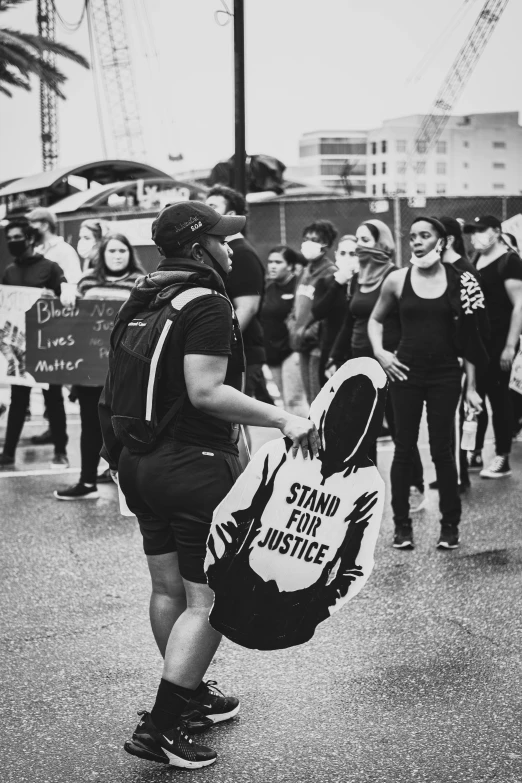 a group of protesters carrying protest signs walk down the street