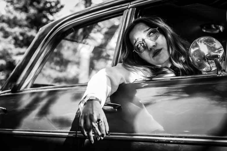 black and white pograph of a woman with painted teeth sticking out of her car