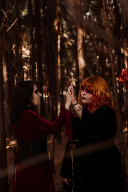 two women in a forest are touching their hands