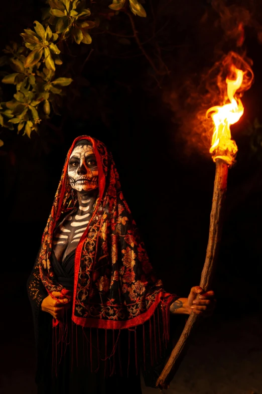 woman dressed in black makeup holds lit stick