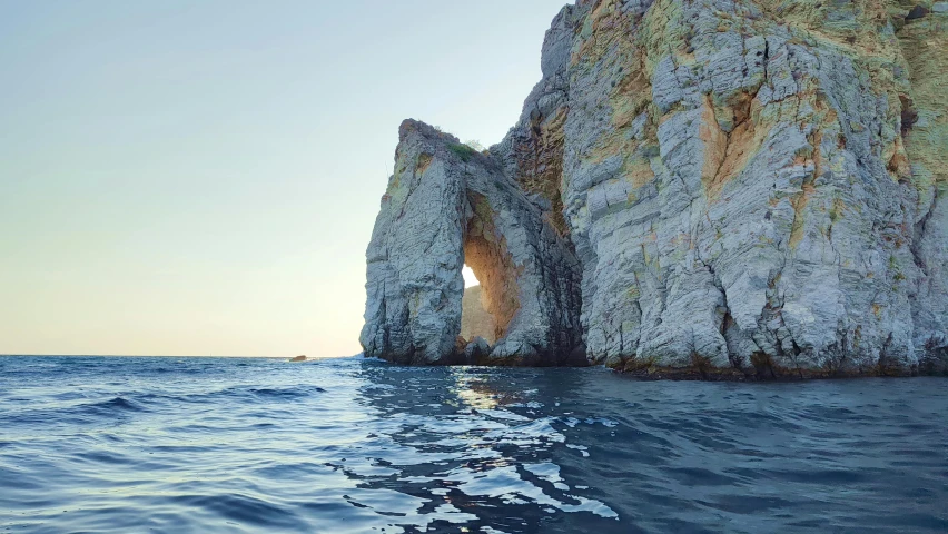 an ocean scene with a rock formation in the water