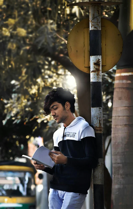 a man is leaning against the corner of the street holding a paper