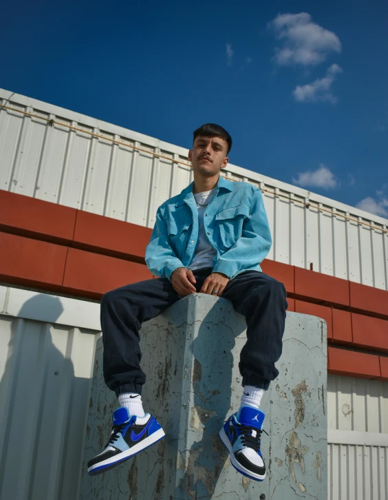 a young man sitting on top of an old concrete wall