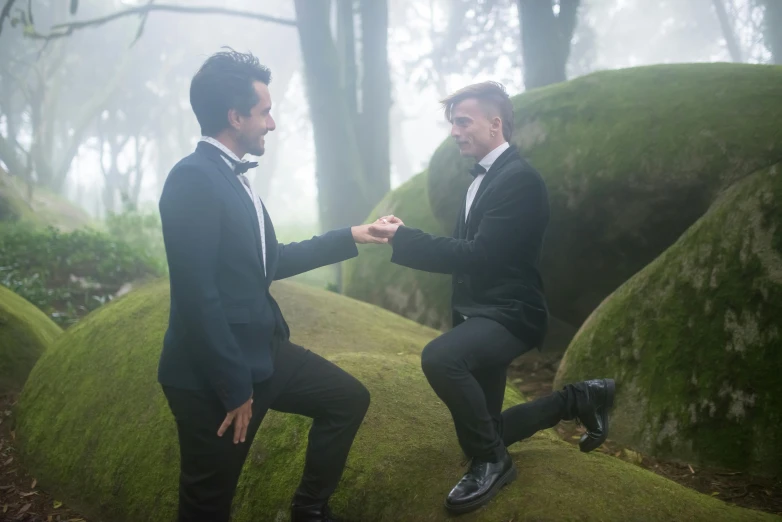 two men in suits on a mossy hill