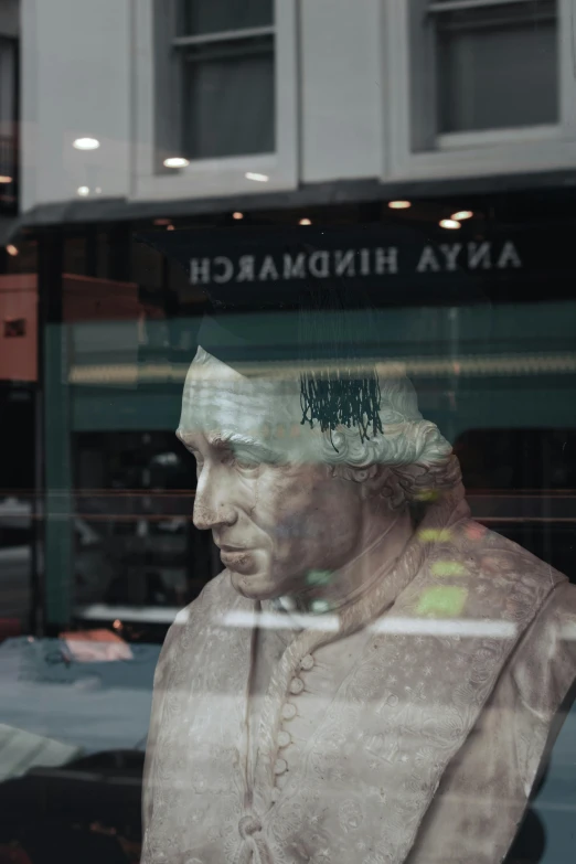 statue outside a large business window on a city street