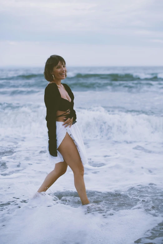 a woman is walking through the water on a beach