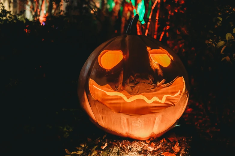 a lighted pumpkin on top of a wood stump