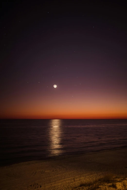 the beach and water at sunset are lit up