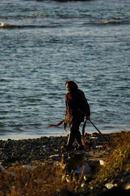 a man is walking alone by the water with poles