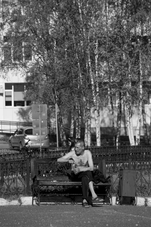 a man is sitting on a bench while looking at his phone