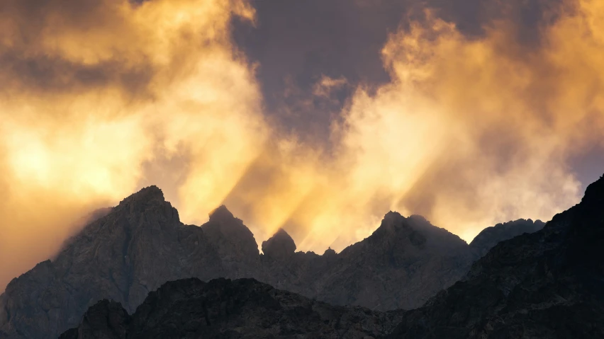 the sunbeams glow through storm clouds in the mountains