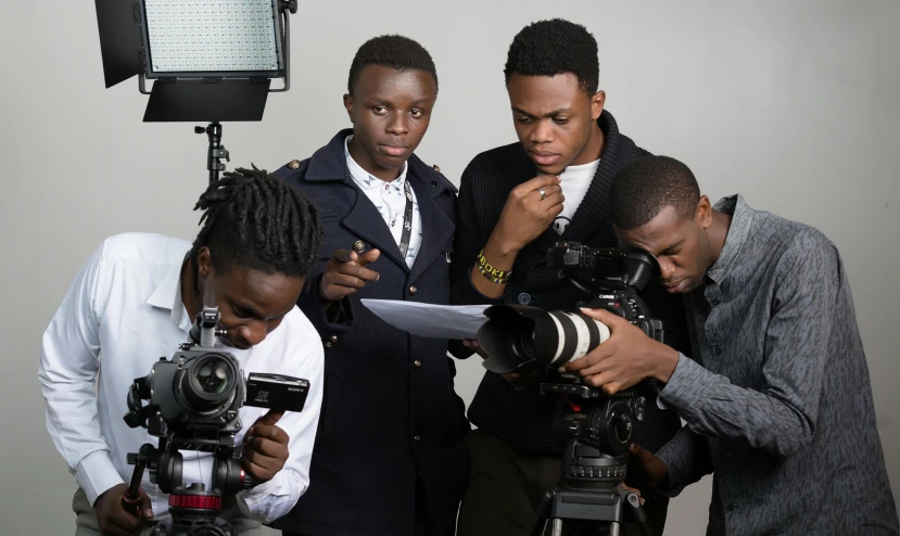 three men take pos while the one woman uses a camera to take a picture