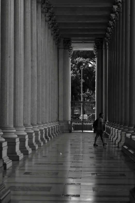 a person standing on the side walk near some pillars