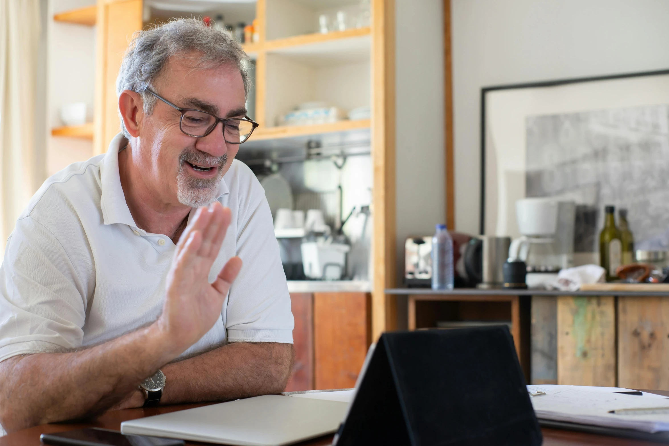 a man with glasses is talking to someone on his laptop