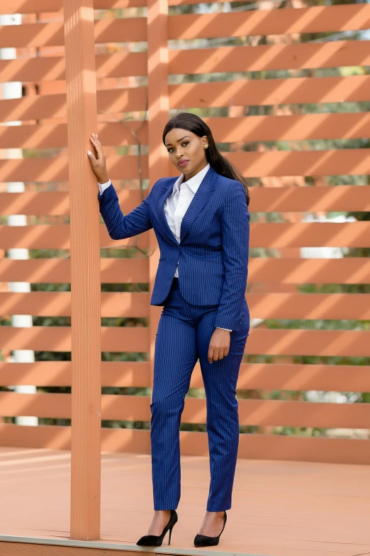 a young woman in a suit is standing next to a pole