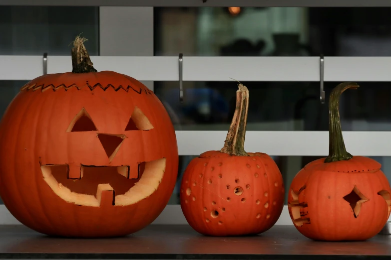 three carved pumpkins are on the mantle