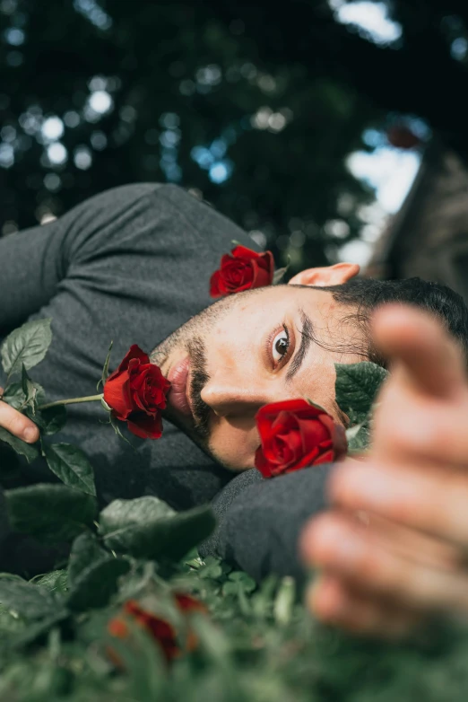 a man looking at a rose behind his head