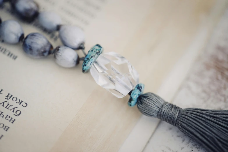 a tasseled bead on a book is resting on a string