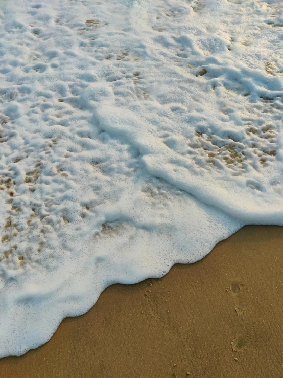 water lapping into a sandy beach under a cloudy sky