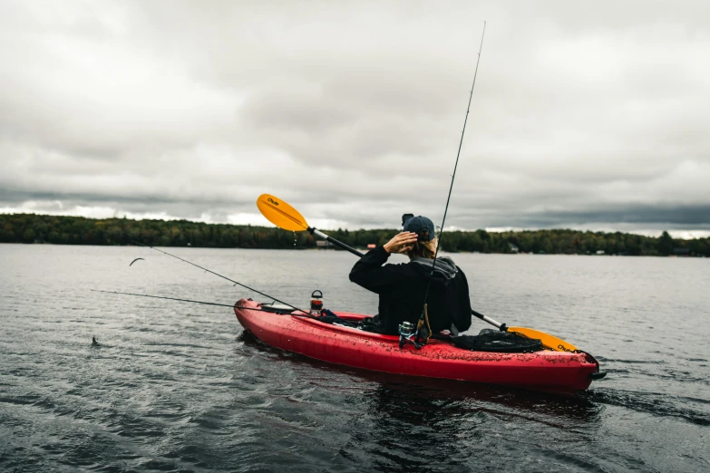 a person on a kayak with a rod and a yellow oar