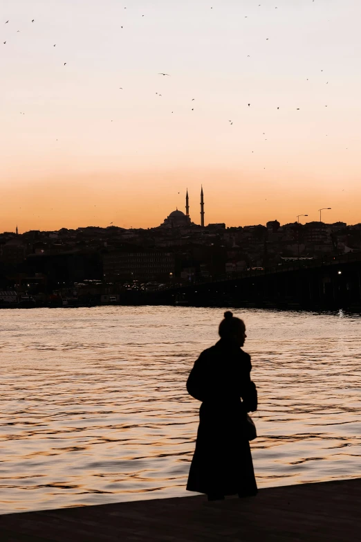 a woman is standing alone by a body of water