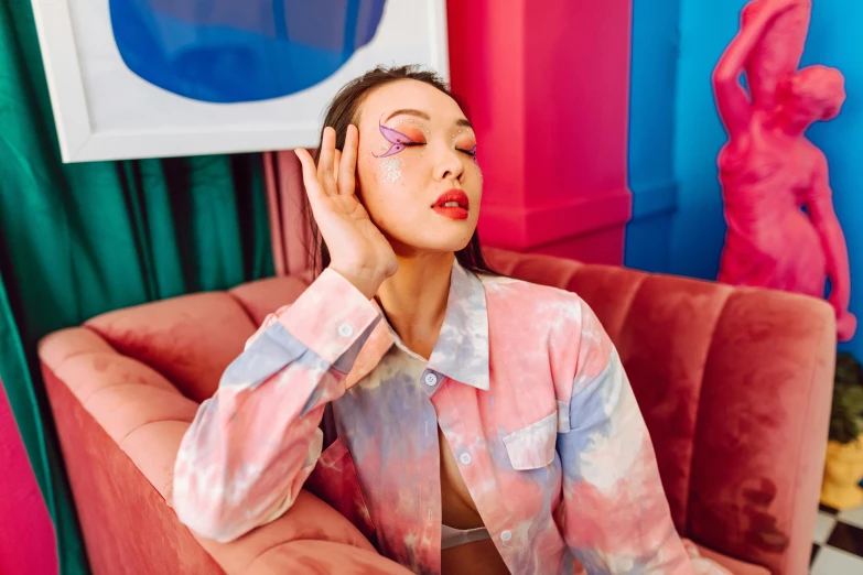 a woman with a pink tie dye shirt holds her head