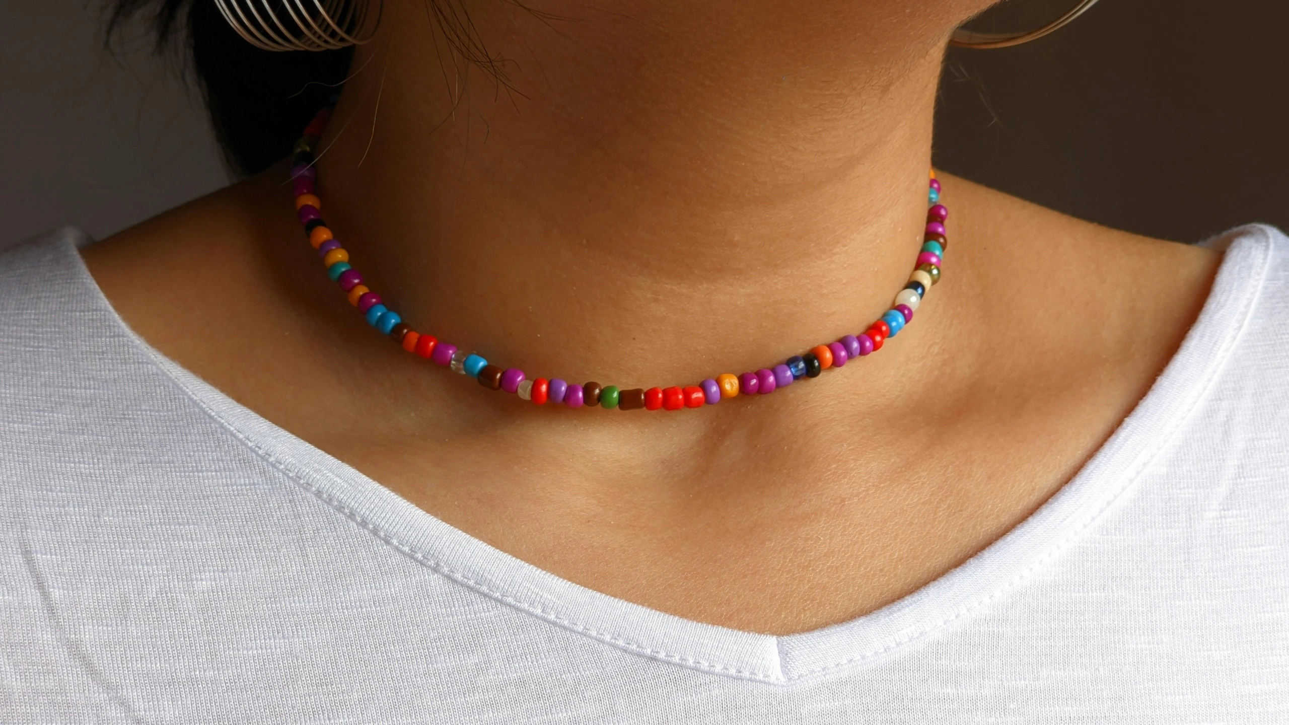 a woman wearing a white shirt and colorful necklace