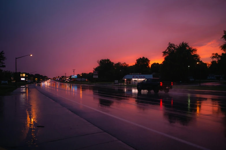 the sun setting on the rain soaked road