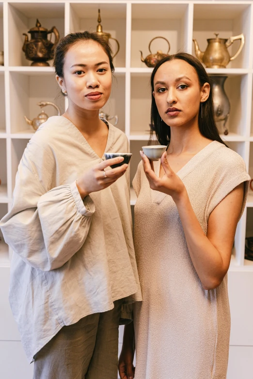 two asian women are standing side by side holding phone