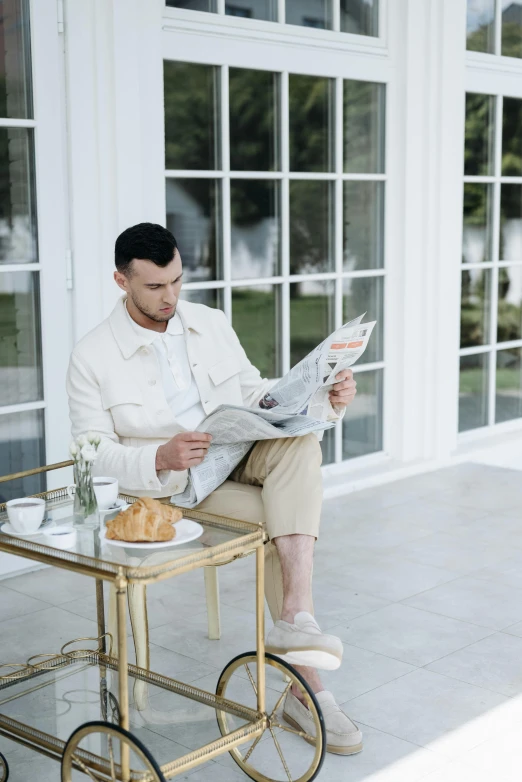 a man sits on a bench and reads the paper while holding a newspaper
