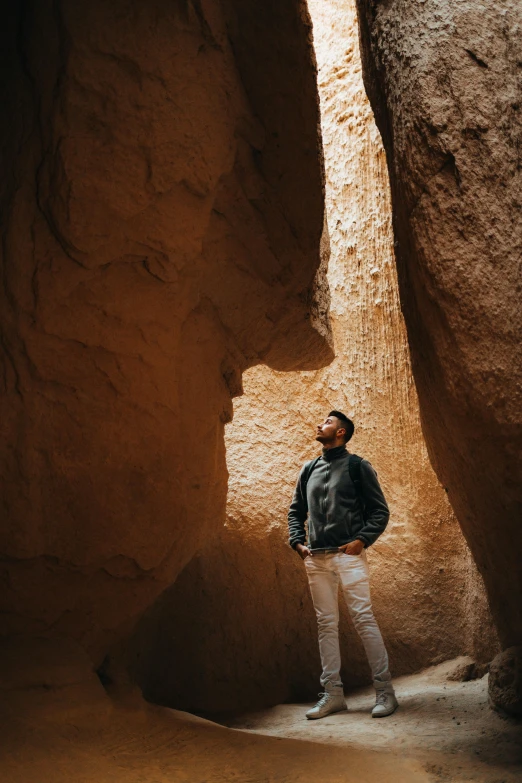 the man stands in between some large rocks