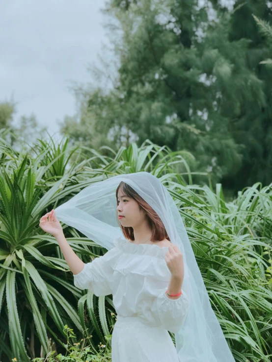 a woman wearing a veil standing outside in a field