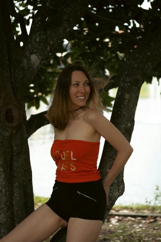 a girl leaning up against a tree while wearing shorts
