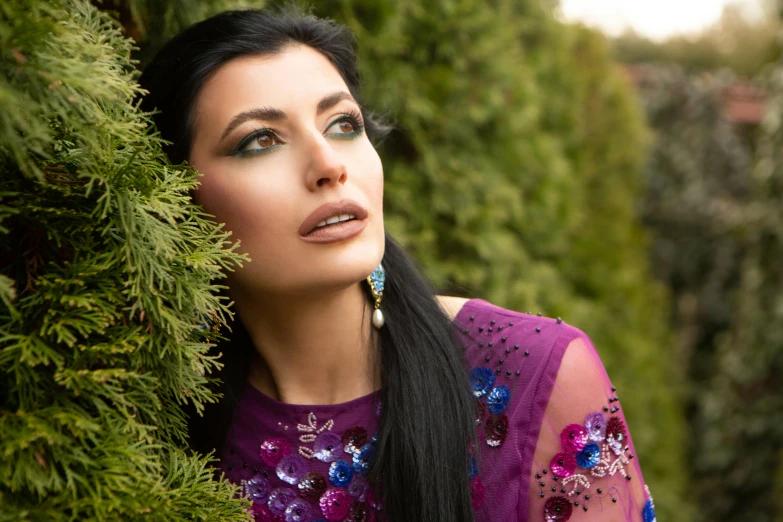 woman in purple dress peeking out from between bushes