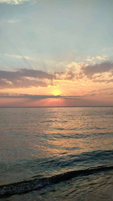 the sun is setting over the water with the sky in background