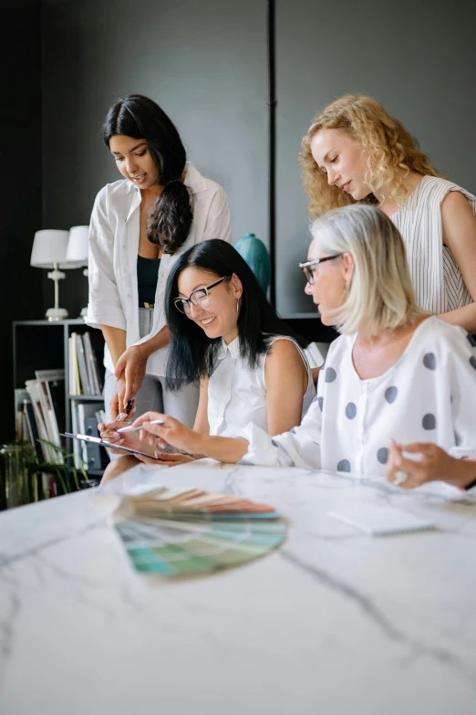 group of women are sitting at a white table