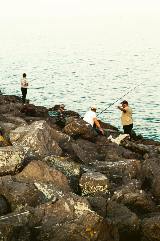 there are people that are fishing on the rocks near the water