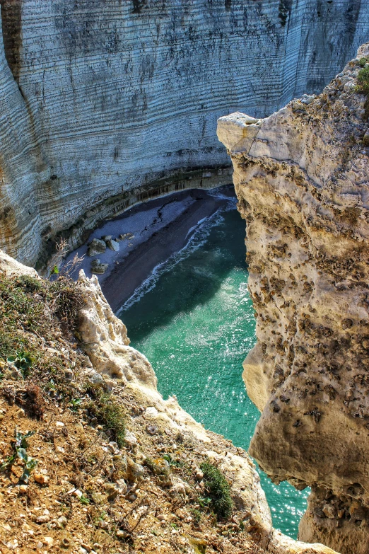 the view from above of a small canyon that has a small bridge over the river