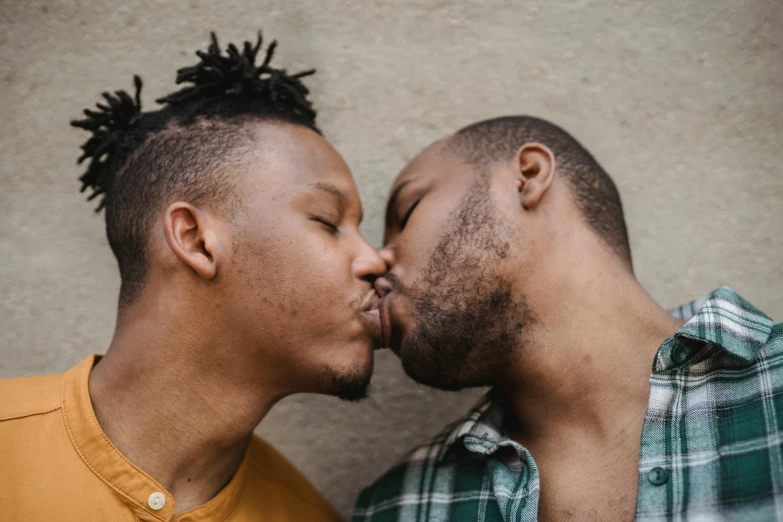 two men kissing each other and one in a green plaid shirt