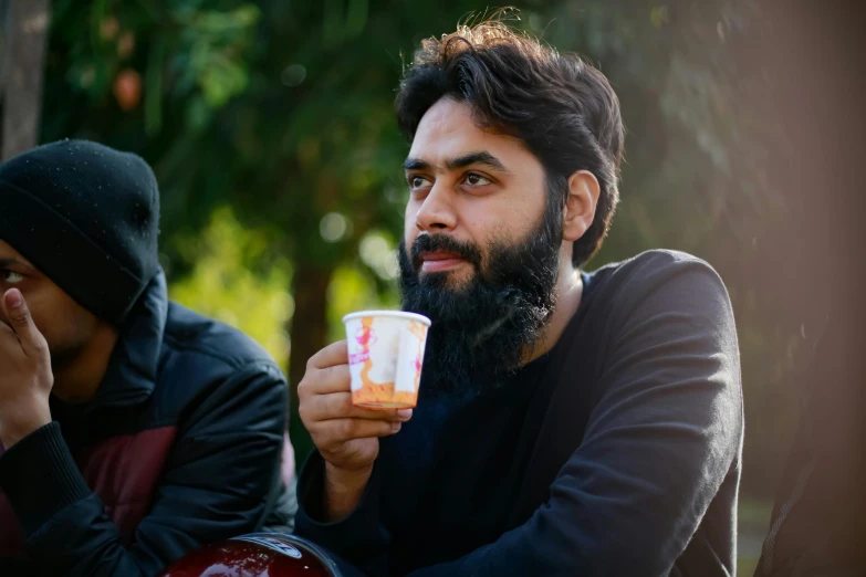 there is a man with a beard holding a coffee cup